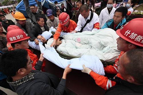 4月21日,救援人员在重灾区四川省宝兴县灵关镇将一名伤者抬出废墟。新华社发(毛健 摄)