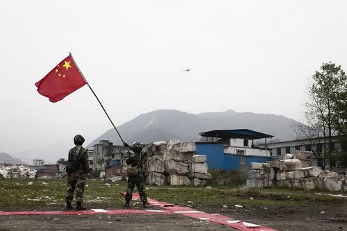 4月21日,两名战士在重灾区四川省宝兴县灵关镇挥舞国旗引导救援直升机。新华社发(毛健 摄)